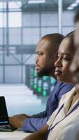 Vertical Focus on server hub employee developing disaster recovery plans ensuring minimal downtime. African american man in data center using data analytics to monitor performance, camera A video