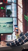 Man at home having fun looking at social media reels done by online content creators. Employee taking break from work to use mobile social network app, screensaver activating on PC, camera A video