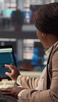 Vertical Confident businesswoman at her office desk working on report writing and answering emails, administrative tasks management. Black female expert reviewing objectives to ensure success. Camera A. video