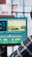 editor wearing headphones doing montage, using specialized software application, zoom in shot. Freelancer using editing tools on PC to cut movie project footage, camera B closeup video