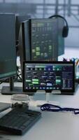 Vertical Electronic devices in empty data center establishment monitoring hardware energy consumption. PC monitors on desk used for checking potential system failures in server room, handheld camera shot video