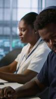 Vertical Engineer in server room looking over documents, developing disaster recovery plans ensuring minimal downtime. Worker reading paperwork in data center, using analytics to monitor performance, camera A video