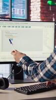 Programmer at desk types code into computer, developing software programs, entering commands. Man at home fixing errors in application, implementing new features pointing to code with pen, camera A video