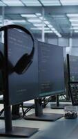 Vertical Electronic devices in empty data center establishment monitoring hardware energy consumption. PC monitors on desk used for checking potential system failures in server room, handheld camera shot video
