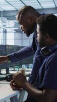 Vertical Data center manager helps intern implement AI predictive maintenance systems. Server farm supervisor checks work done by employee using artificial intelligence to identify hardware failures, camera A video