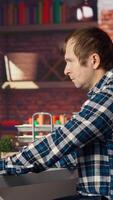 Man at home looking over documentation files to learn how to use text to generative models. Person in apartment reading technical specifications documents for AI program, camera B video