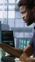 Vertical Machine learning expert in data center maintaining company network infrastructure. Worker using artificial intelligence server hub to ensure optimal system performance, camera A video