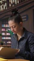 Vertical Woman tutor reading a book and doing a brief to complete her notes, creating accurate learning materials for her private lessons and mentoring in an academic environment. Camera A. video