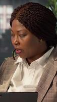 Vertical Black manager reviews company strategy with her female assistant in a high end corporate office, making key business decisions to support organizational growth. Discuss resource allocation. Camera A. video