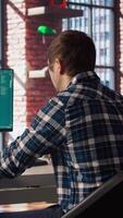 Man seated at desk using AI LLM chatbot software in modern urban home office. Person requesting help from large language model program on computer in bright apartment workspace, camera A video