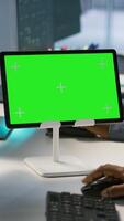 Vertical Close up of green tablet in server room used by system administrators to ensure minimal downtime. Data center software developers looking at chroma key device, monitoring performance, camera A video