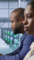 Vertical System administrators in data center implementing AI systems. Server farm specialists using artificial intelligence to identify hardware failures impacting operations, camera A handheld camera shot video