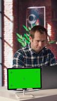 Mockup tablet next to worker listening music, analyzing data on laptop at desk, compiling reports. Isolated screen device next to employee putting headphones on, using notebook device, camera A video
