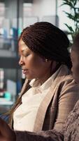 Vertical General manager reviews financial forecasts with an employee at desk, leading a session on project development and corporate goals. Collaborating to meet business objectives. Camera A. video