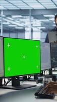 Vertical System administrator in server hub ensuring data remains shielded from potential threats using chroma key PC. Woman safeguarding data center against hackers with mockup computer, camera A video