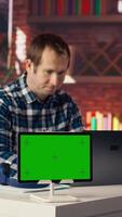 Mockup tablet next to worker listening music, analyzing data on laptop at desk, compiling reports. Isolated screen device next to employee putting headphones on, using notebook device, camera B video