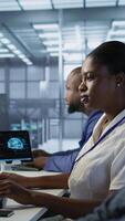 Vertical Data center engineer wearing headphones enjoying songs, maintaining company network infrastructure. Woman in server hub listening music while ensuring optimal system performance, camera A video