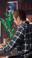 Man in home office stretches back while looking at UI on PC screen, feeling fatigued while executing programming code. IT developer feeling backpain, relieving pain, writing and testing code, camera A video