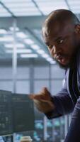 Vertical Data center manager helps intern implement AI predictive maintenance systems. Server farm supervisor checks work done by employee using artificial intelligence to identify hardware failures, camera A video
