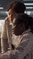 Vertical African american CEO and employee review company numbers, creating a roadmap that includes goals, strategies and resource allocation management. Specialists meet corporate objectives. Camera A. video