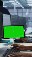 Vertical Team of programmer using green screen tablet, working in server farm to optimize it for data processing requirements. Teamworking colleagues coding on chroma key device in data center, camera A video