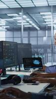 Vertical Woman putting headphones on in server room, developing disaster recovery plans ensuring minimal downtime. Engineer listening music in data center, using data analytics to monitor performance, camera A video