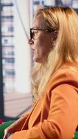 Vertical Determined businesswoman speaking on a phone call to ensure project development success, multitasking in a corporate office. Female CEO using remote connection on her smartphone. Camera A. video