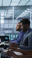Vertical Computer scientists in data center implementing AI predictive maintenance systems. Server farm employees using artificial intelligence to identify hardware failures impacting operations, camera A video