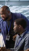 Vertical Data center team leader supervising engineers implementing AI predictive maintenance systems. Server farm boss overseeing workers using artificial intelligence to identify hardware failures, camera A video