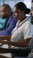 Vertical Technicians using computers and tablet in data center, implementing AI systems. Server farm experts using artificial intelligence on device to identify hardware failures impacting operations, camera A video