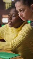 Vertical Multiethnic scholars in the library engaged in remote learning with their mentor, participating in a conference with other students for an assignment. Pupils attend online webinar. Camera A. video