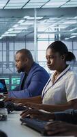 Vertical Technicians using computers and tablet in data center, implementing AI systems. Server farm experts using artificial intelligence on device to identify hardware failures impacting operations, camera A video