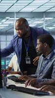 Vertical Data center team leader supervising engineers implementing AI predictive maintenance systems. Server farm boss overseeing workers using artificial intelligence to identify hardware failures, camera A video
