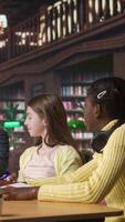 Vertical Elementary school pupils working with a professor solving exercises for the class homework, developing learning skills at a study desk. Tutor explains the curriculum materials to girls. Camera A. video