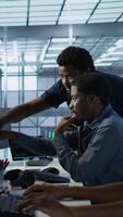 Vertical Manager supervising server room workers developing disaster recovery plans ensuring minimal downtime. Supervisor oversees data center technicians using data analytics to monitor performance, camera A video