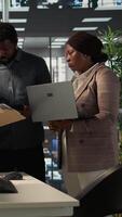 Vertical Multinational company workers meet to plan a project focused on growth, discussing resource allocation and performance metrics data. Black business staff achieve goals effectively. Camera B. video