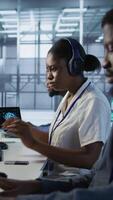 Vertical Coworker giving server hub engineer insights into developing disaster recovery plans ensuring minimal downtime. Worker helping colleague in data center monitoring performance, camera A video
