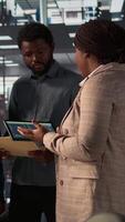 Vertical Black leader reviews company strategy with her team members in a modern corporate office, making key business decisions to support organizational growth. Discuss resource allocation. Camera B. video