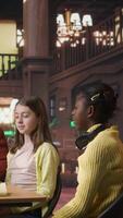 Vertical Cheerful diverse classmates sharing a high five during private lessons with tutor in the library, finishing team project. Elementary school pupils feeling satisfied with academic progress. Camera A. video
