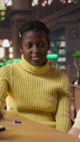 Vertical Cute preadolescent girls gossiping and hugging each other in the library, takes break from school work and enjoying assignment together. Young scholars laughing and enjoying chat. Camera A. video