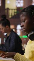 Vertical Black preteen pupil underlining key words and phrases for the learning session at the library, creating a summary to retain information easier. Focused scholar studying. Camera B. video