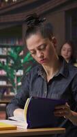 Vertical Professional author and librarian working on new notes in a public library, focused on academic resources and guidance for success. Woman collecting educational information. Camera A. video