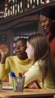 Vertical Elementary school pupils and tutor attend a live online course lesson from the library desk, connected via webcam to other classmates in a mentoring session. Virtual webinar discussion. Camera A. video