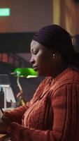 Vertical Confident tutor reading her notes and preparing teaching materials at a library desk, showcasing her dedication to pedagogy and mentoring. Establishing private lessons for academic support. Camera A. video