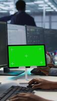 Vertical Close up of green tablet in server room used by system administrators to ensure minimal downtime. Data center software developers looking at chroma key device, monitoring performance, camera A video