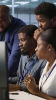 Vertical Teamworking engineers talking in server room, developing disaster recovery plans ensuring minimal downtime. Team of data center employees doing brainstorming, monitoring performance, camera A video