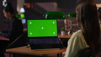 Focused schoolgirl engaged in academic tasks with green screen at a library, working on school assignments with her laptop. Solving class work tasks, searches information on internet. Camera B. video