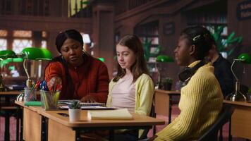 glad olika klasskamrater delning en hög fem under privat lektioner med handledare i de bibliotek, efterbehandling team projekt. elementärt skola elever känsla nöjd med akademisk framsteg. kamera b. video