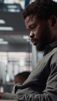 Vertical African american specialist on a landline phone call negotiating funds at his desk, managing an expansion project and discussing growth strategies. CEO multitasking for a career success. Camera A. video