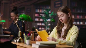 Young teen girl engrossed in reading books at the school library, focusing on literature and knowledge while she is preparing for her academic lessons and other class assignments. Camera B. video
